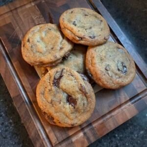 chocolate chunk cookies on dark cutting board fir and maple