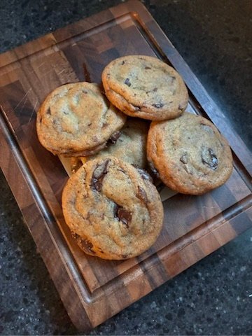 chocolate chunk cookies on dark cutting board fir and maple